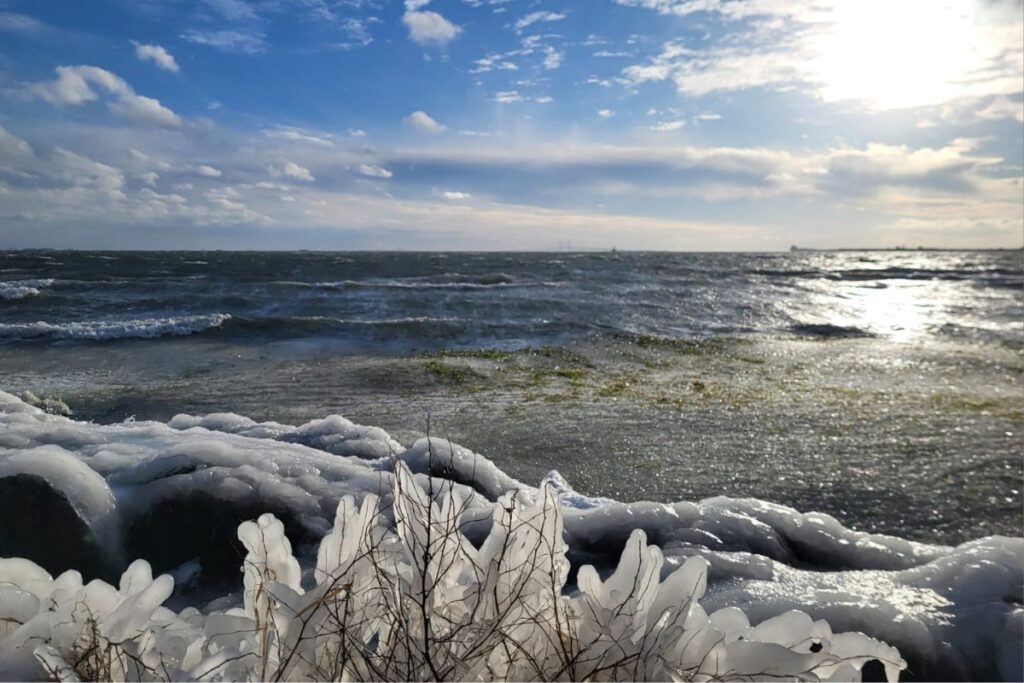 Zwei Personen im flachen Wasser am Ufer, winterliche Szene