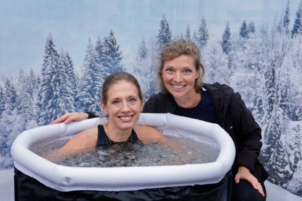 Teilnehmerin in der Eiswanne, daneben Dr. med. Anne Passers, im Hintergrund Winterkulisse