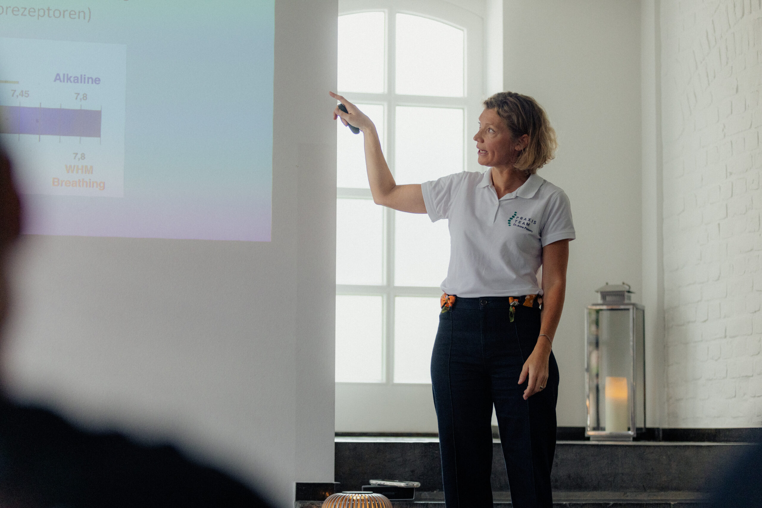 Dr. med. Anne Passers hält einen Vortrag vor einer Präsentationsleinwand